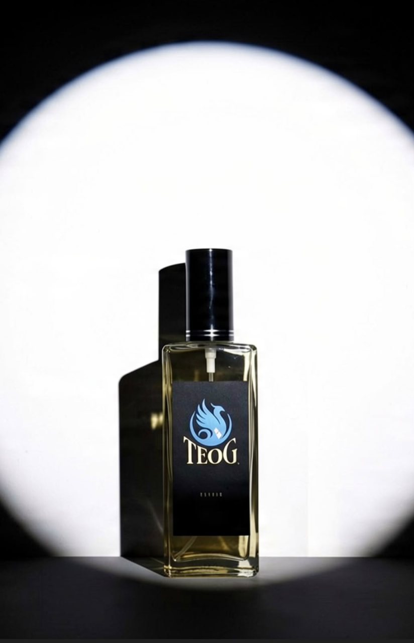 Frasco TEOG de vidrio con tapa negra y etiqueta negra con el fénix azul, bajo un foco de luz